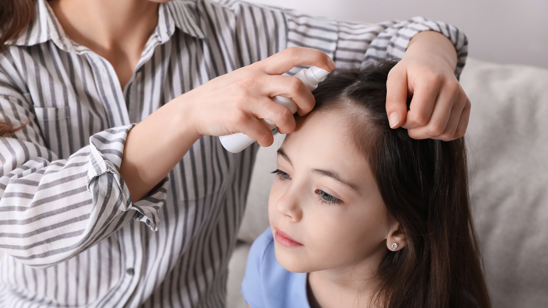 Parent applying a natural hair spray treatment while reviewing lice options