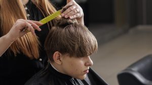 Stylist combing a young boy's hair during a haircut at a kids' hair salon