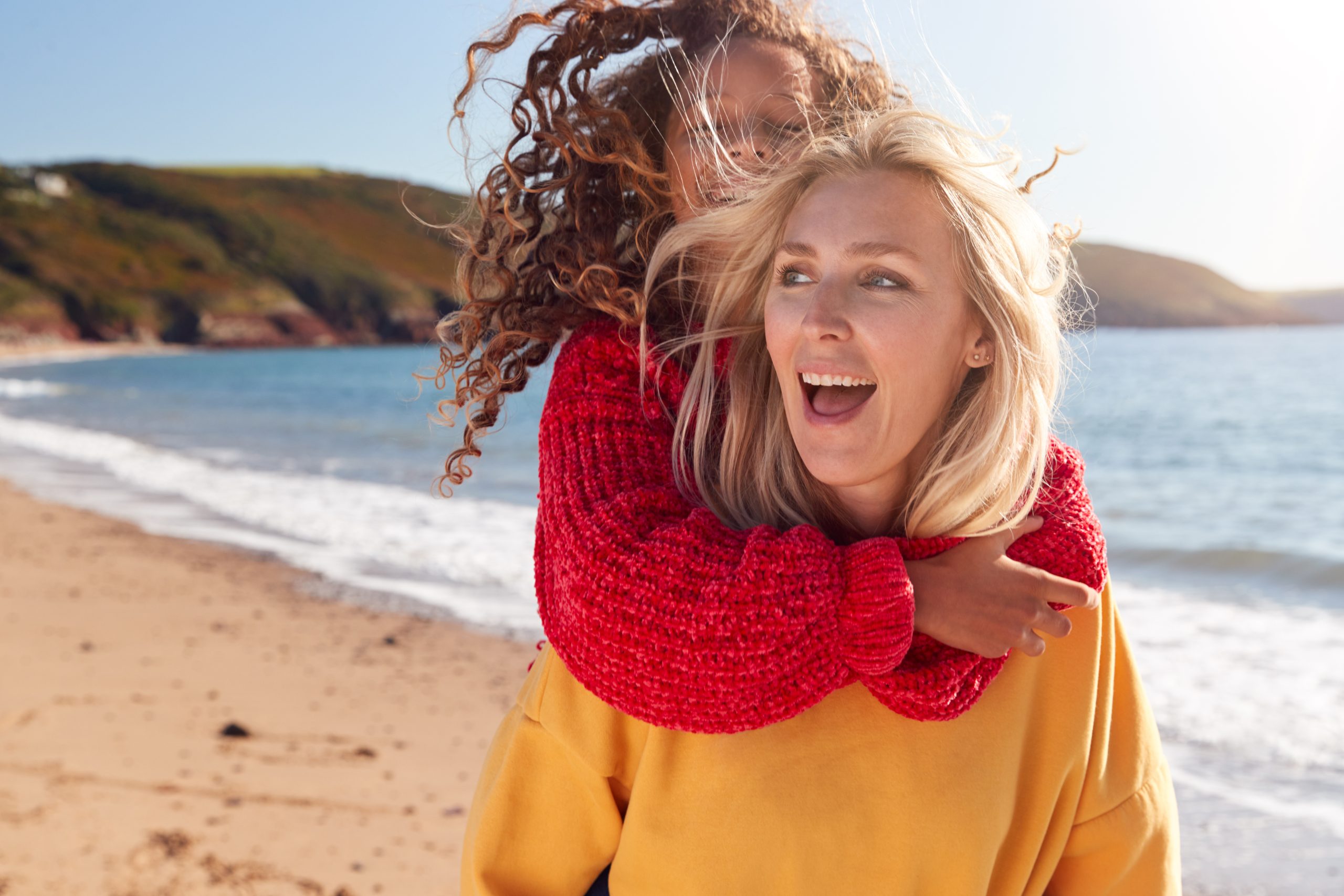 Mother and child on a winter beach break for January head lice guidance