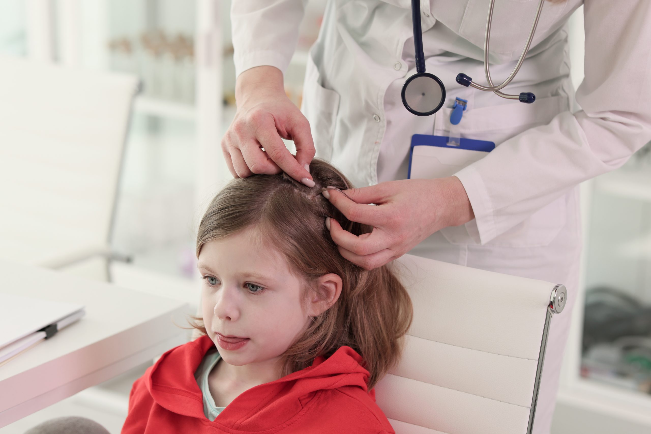 A lice technician gently parts a young child's hair to inspect the scalp for nits and live lice.