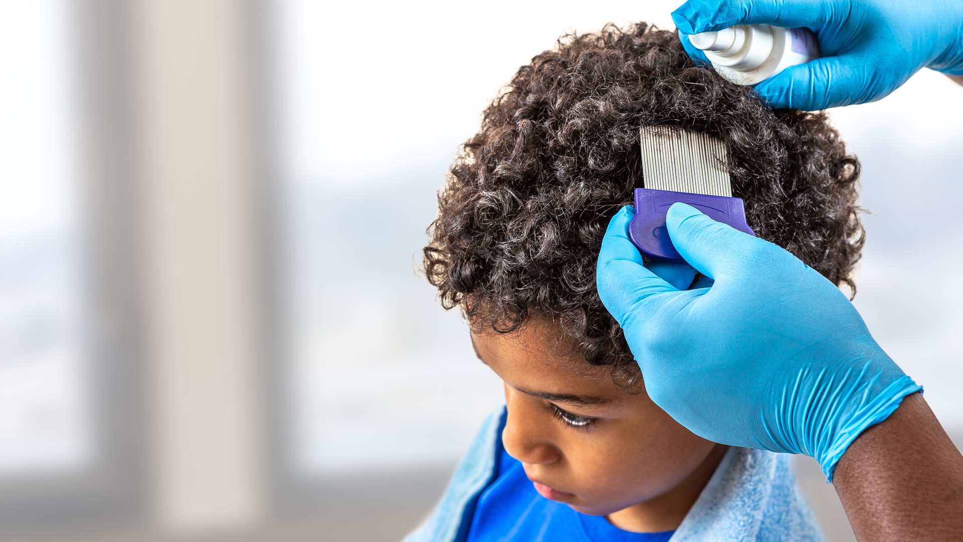 Parent parting a child's hair during a lice outbreak check